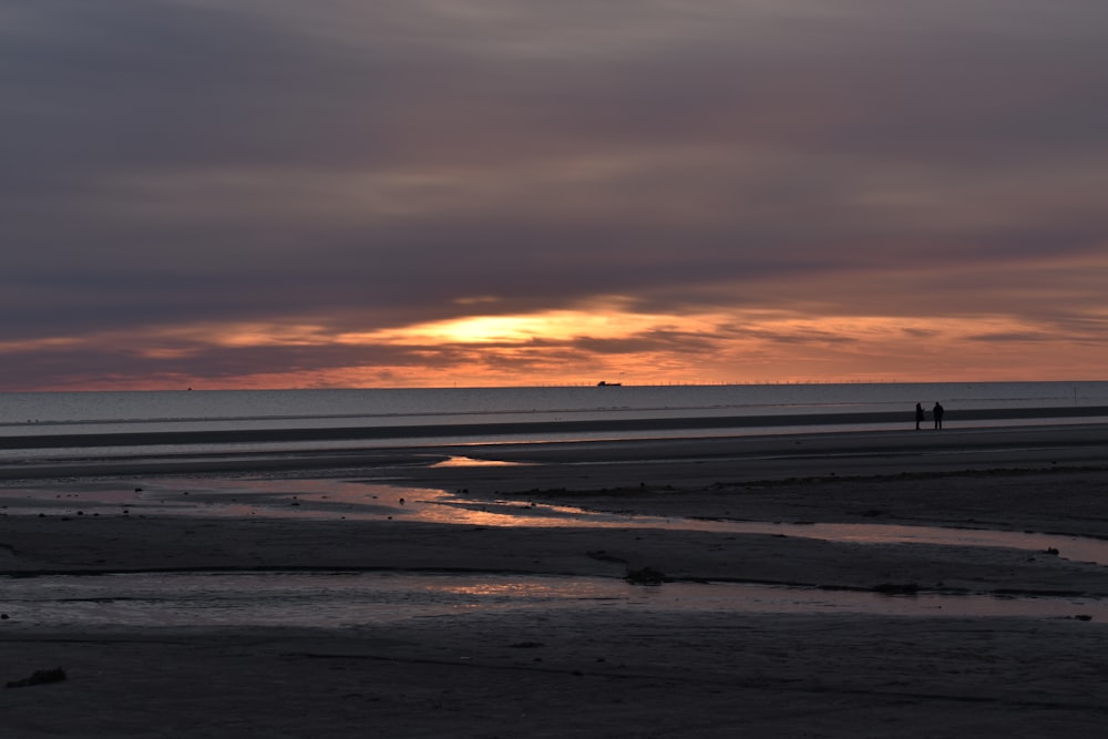 the sun is setting over the water at the beach