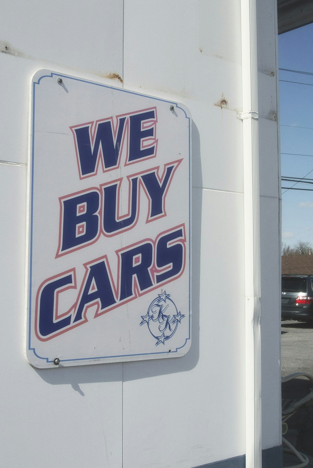 a sign that says we buy cars on the side of a building