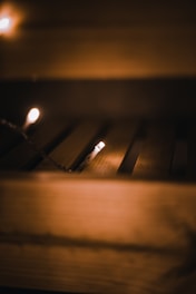 A warm, dimly-lit wooden surface with soft yellow fairy lights. The light casts gentle shadows, creating a cozy and intimate atmosphere.