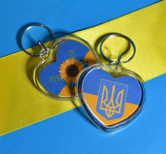 a couple of key ring pentant sitting on top of a blue and yellow ribbon