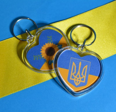 a couple of key ring pentant sitting on top of a blue and yellow ribbon