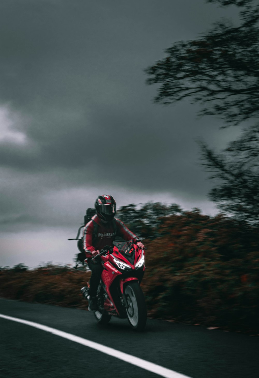 Un hombre conduciendo una motocicleta roja por una carretera con curvas