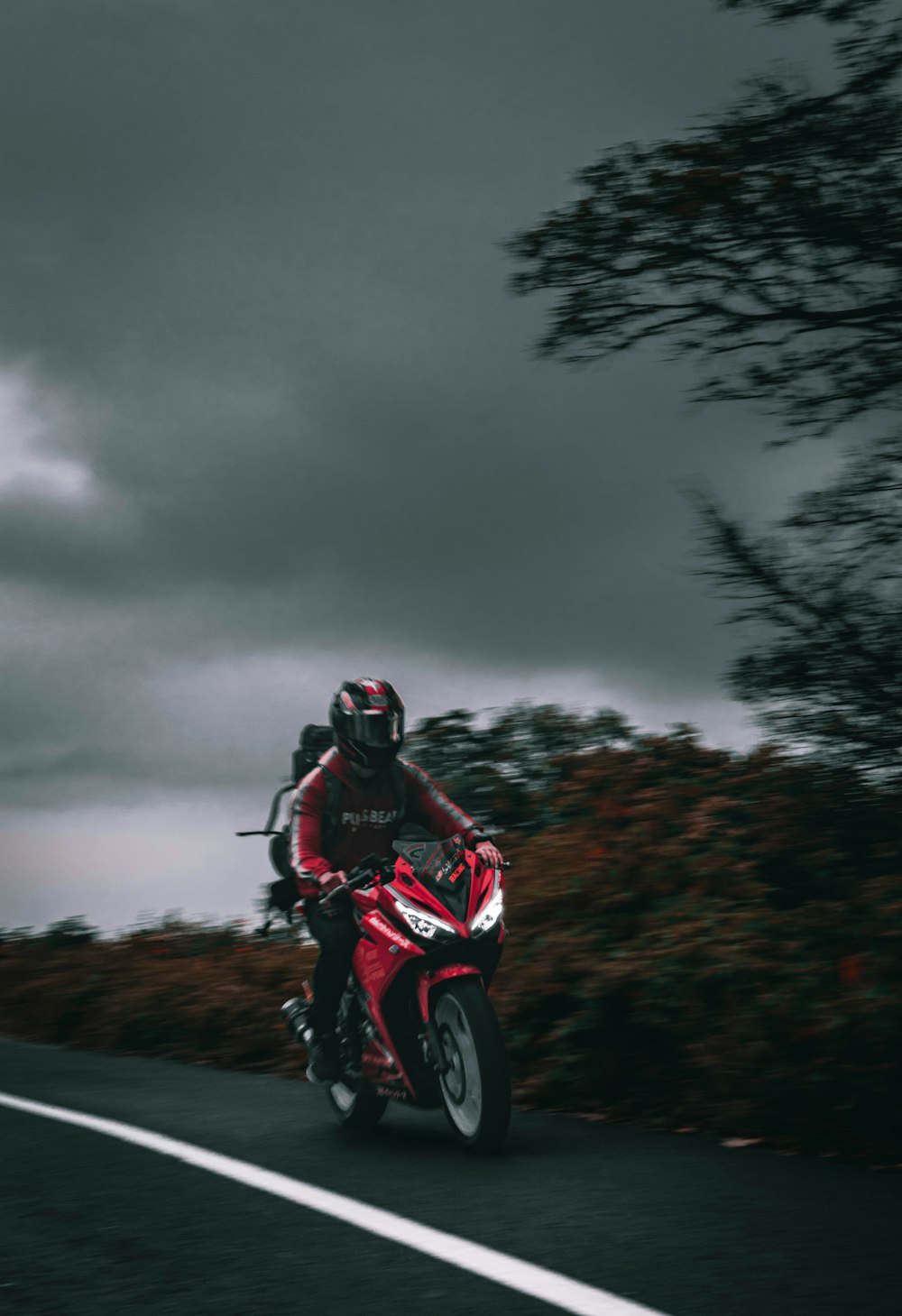 a man riding a red motorcycle down a curvy road