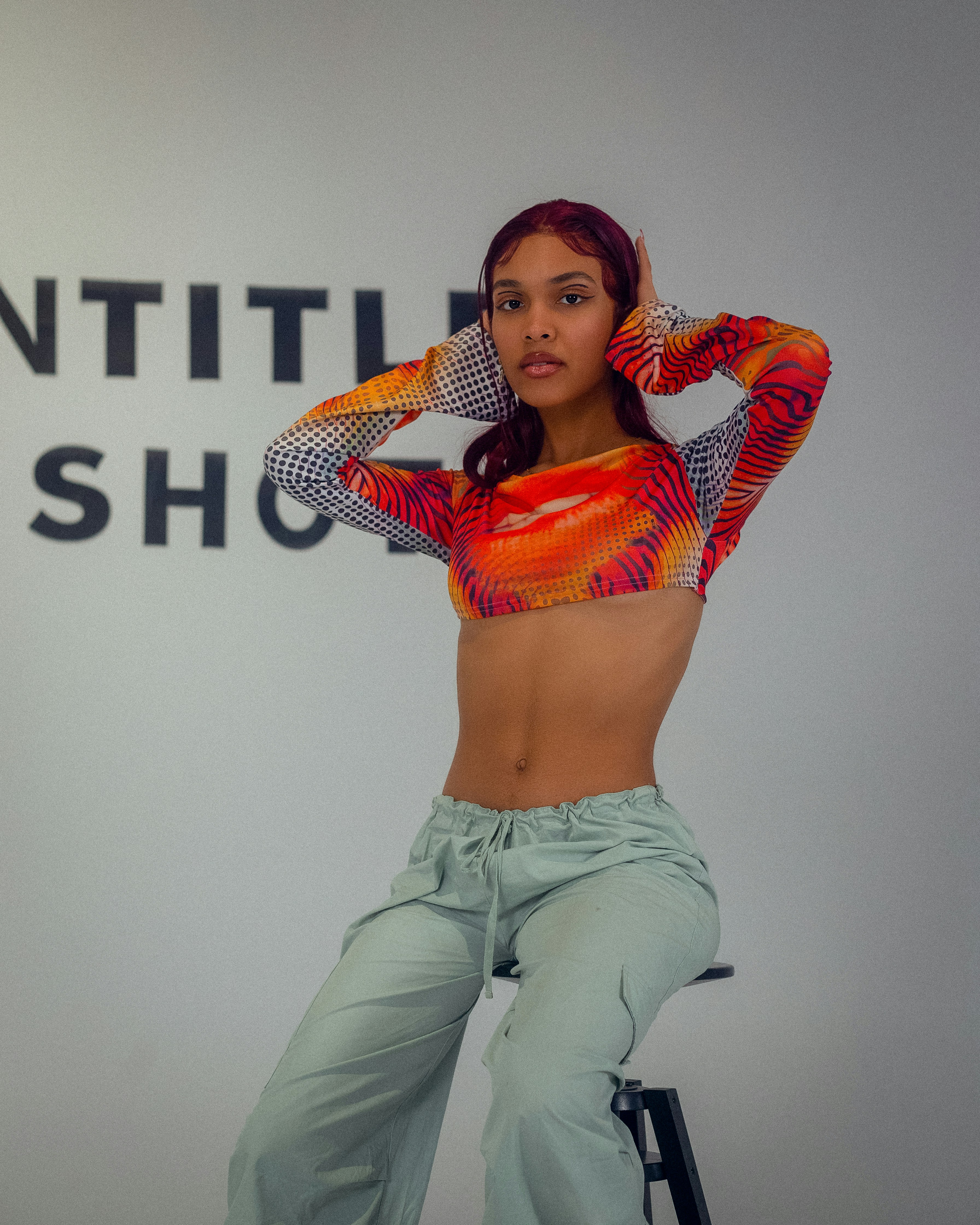 a woman posing in front of a sign with her hands on her head