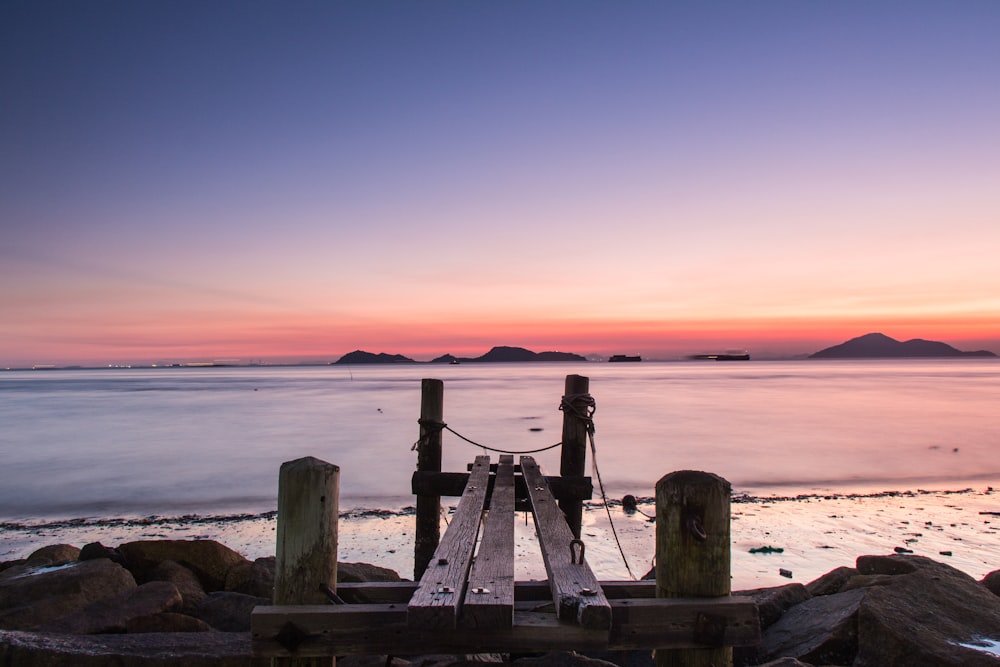 a wooden dock sitting on top of a beach next to the ocean