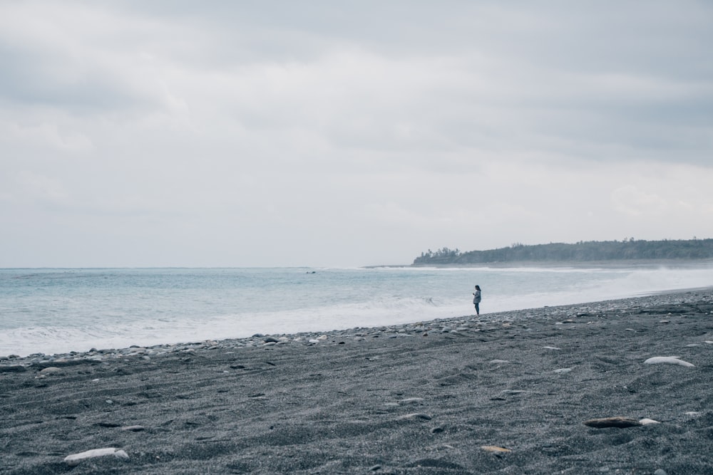 a person standing on a beach next to the ocean