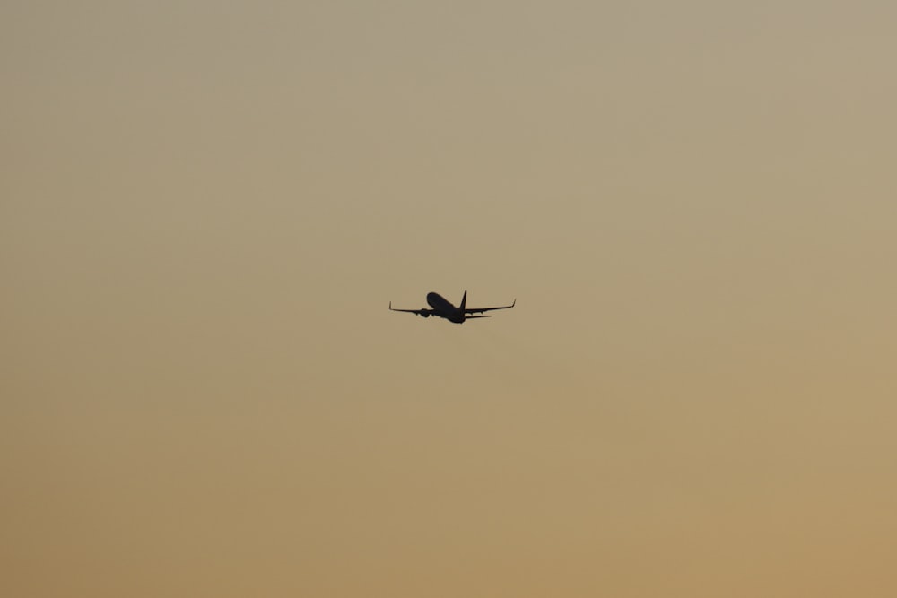 an airplane is flying in the sky at sunset