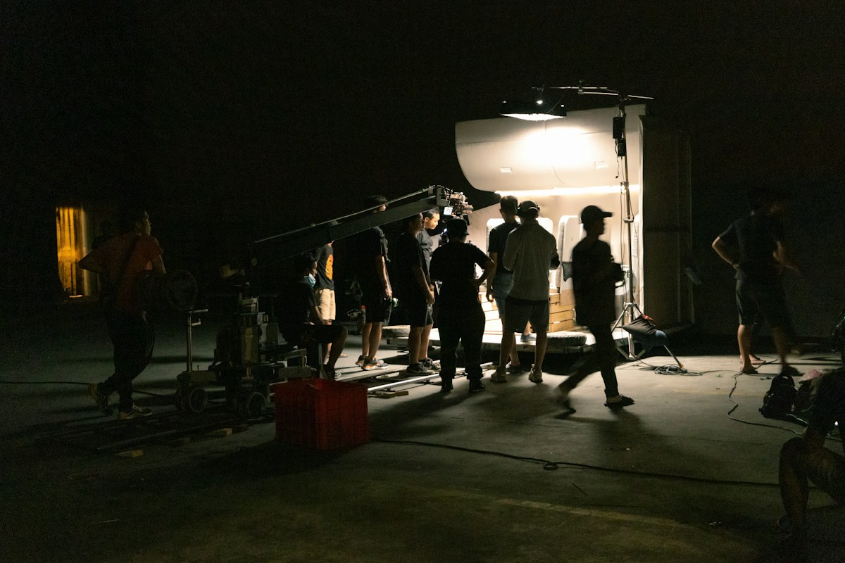 Film crew gathered around a camera under a single light at night, placeholder production image