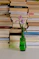 a green vase with a flower in front of a stack of books