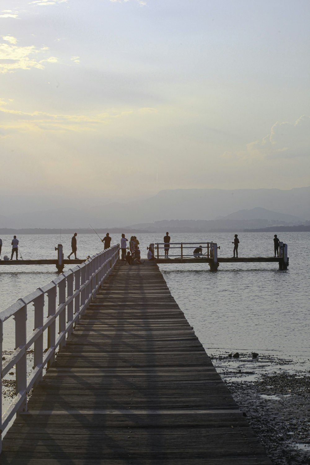 a group of people standing on a pier next to a body of water