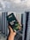 A hand holding a box of Dilmah Ceylon Tea, prominently displayed against a background of high-rise buildings under a cloudy sky. The tea box is dark green with images of tea leaves and a small cup of tea, containing details about the tea blend.