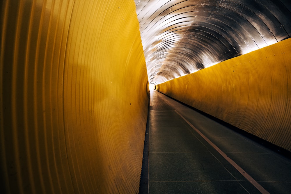 a long tunnel with a yellow wall and a light at the end
