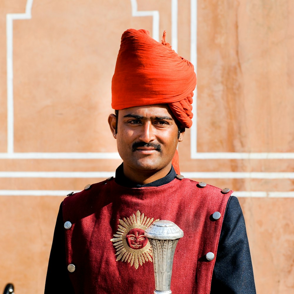 a man in a red turban stands in front of a building