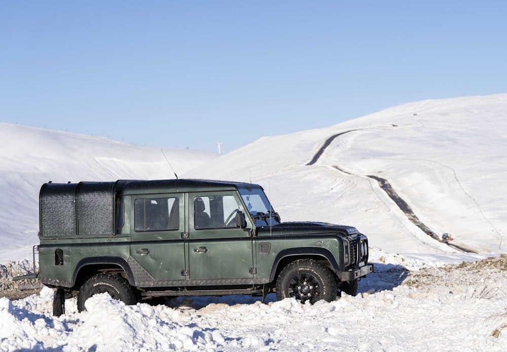 a green jeep is parked in the snow
