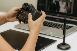 a person holding a camera in front of a laptop