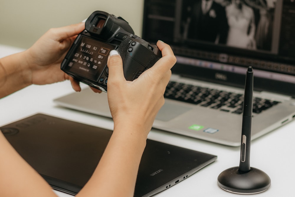 una persona che tiene una telecamera davanti a un laptop