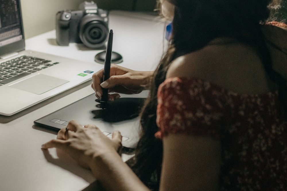 a woman sitting at a desk writing on a piece of paper