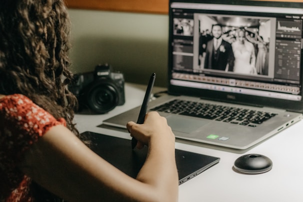 A photo editor carefully retouching a wedding portrait on a computer screen.