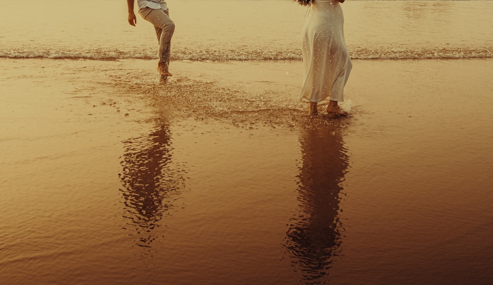 a couple of people standing on top of a beach