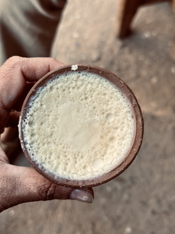 Close-up of fresh milk being poured into a clay pot, highlighting its creamy texture.