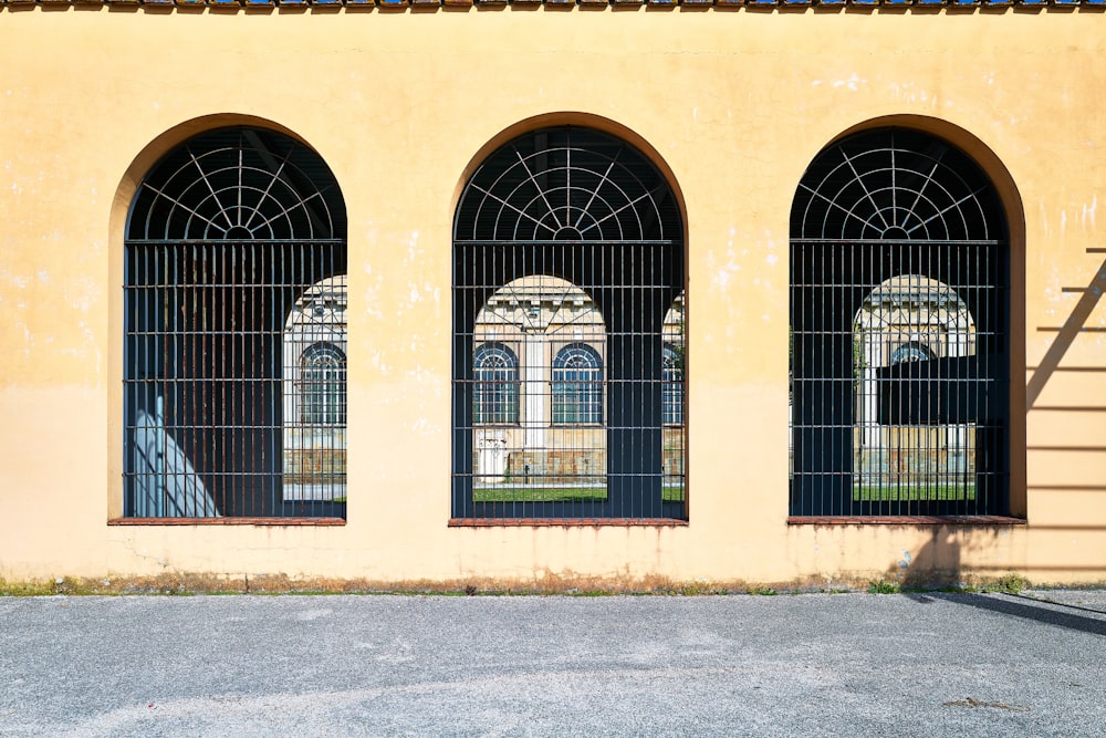 a yellow building with three windows and a ladder