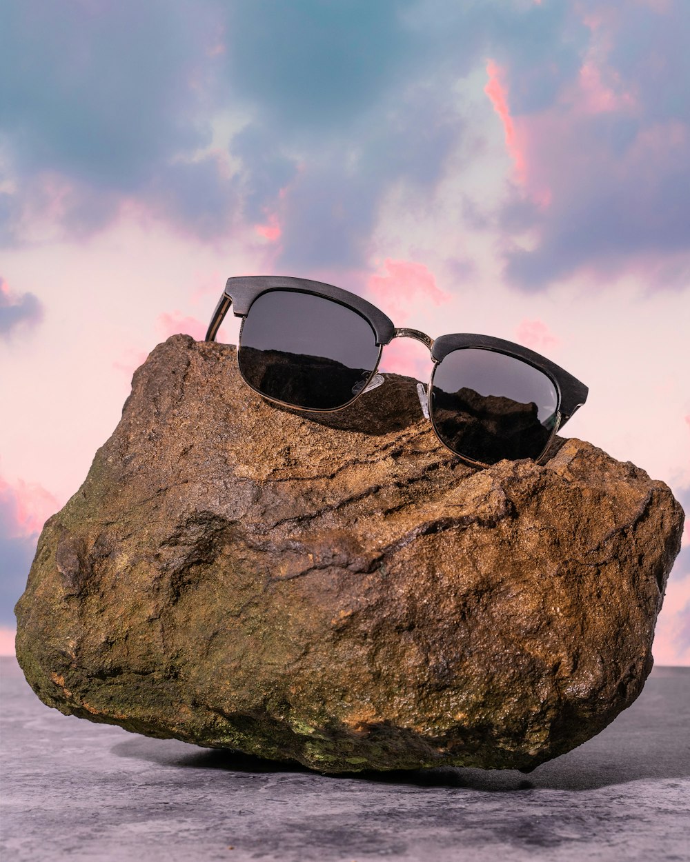 a pair of sunglasses sitting on top of a rock