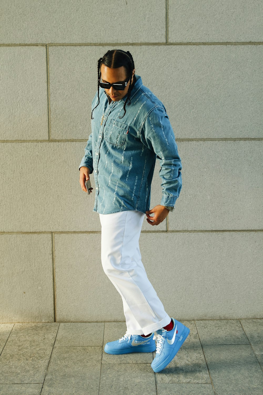 a man in a denim shirt and white pants is walking