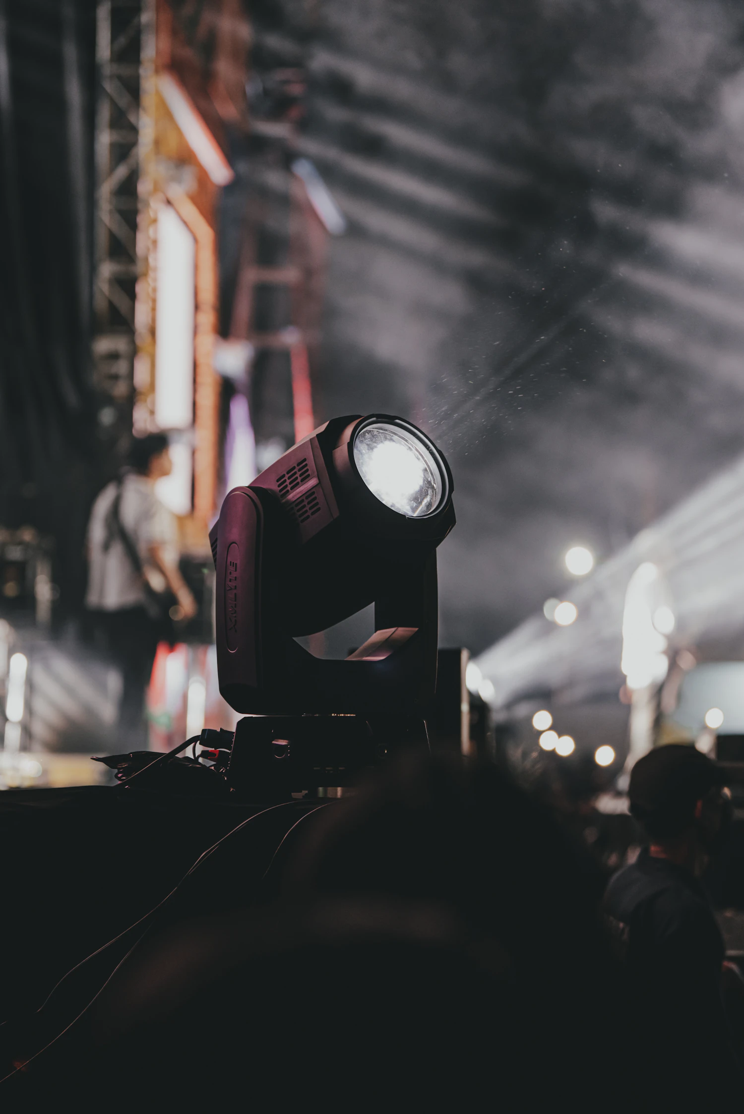 A stage fixture burning through haze above an empty hall