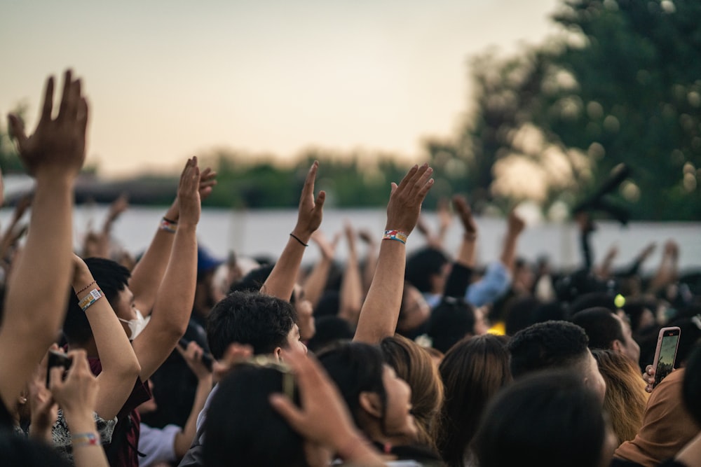 a crowd of people raising their hands in the air