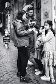 A candid shot of a family enjoying takeaway meals together on a shaded bench near the store.