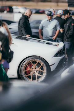 A group of diverse car influencers gathered around a luxury vehicle sharing ideas and laughter.