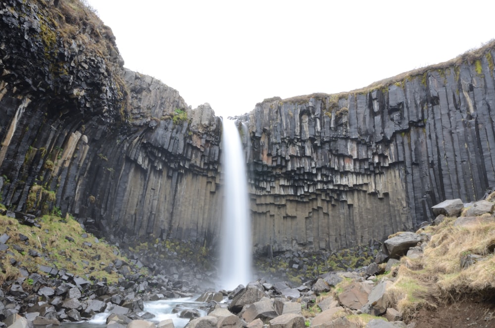 a waterfall is seen in the middle of a rocky area