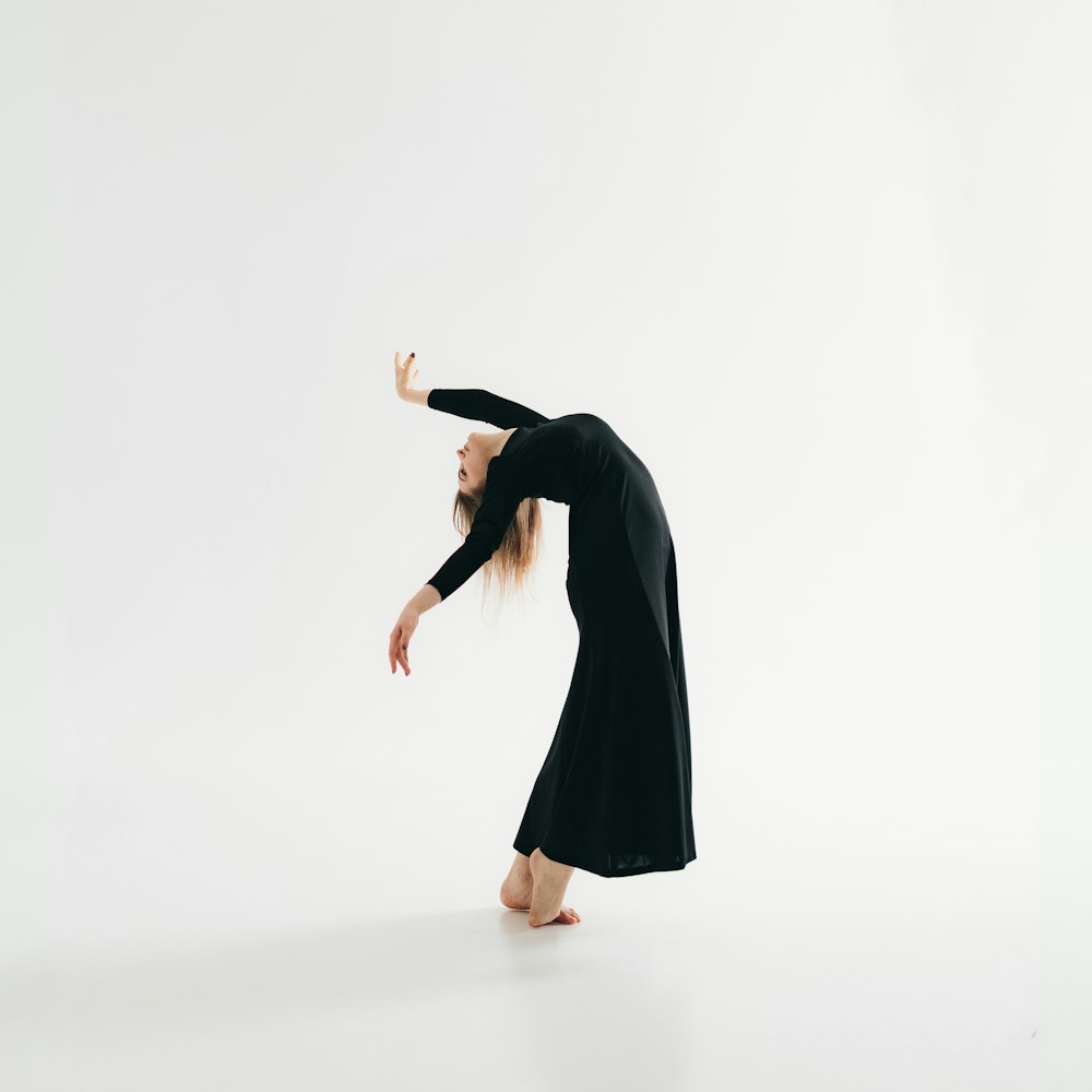 a woman in a black dress is doing a handstand