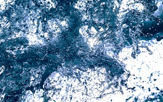A dynamic splash of water captured mid-motion, with water droplets suspended in the air against a bright background.