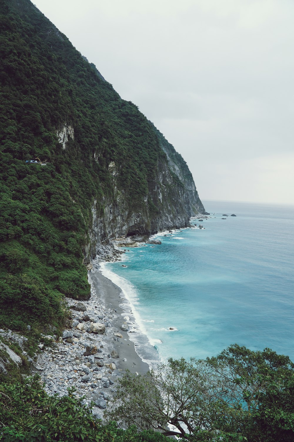 a rocky beach next to the ocean on a cloudy day