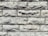 A close-up view of a textured stone wall featuring rectangular blocks stacked with visible rough and rugged surfaces. The stones display a natural, uneven alignment, adding to the rustic appearance.