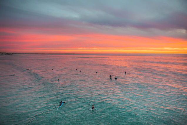 A vibrant photo of surfers catching waves at sunset, with redflip surfwear visible on some riders.