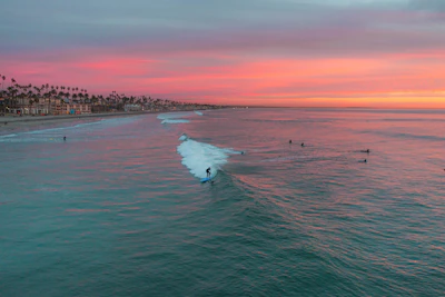 Sunset view over the beach in Sayulita with surfers catching waves and palm trees swaying.