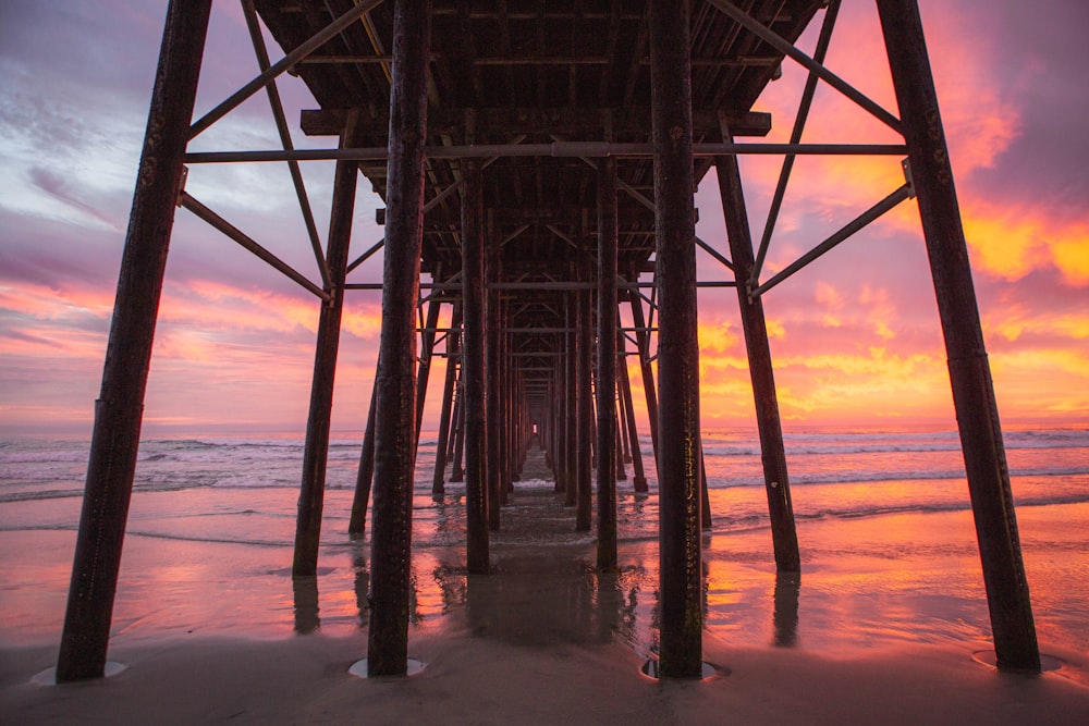 a view of the underside of a pier at sunset