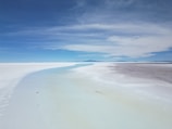 A vibrant salt flat landscape under a clear blue sky.