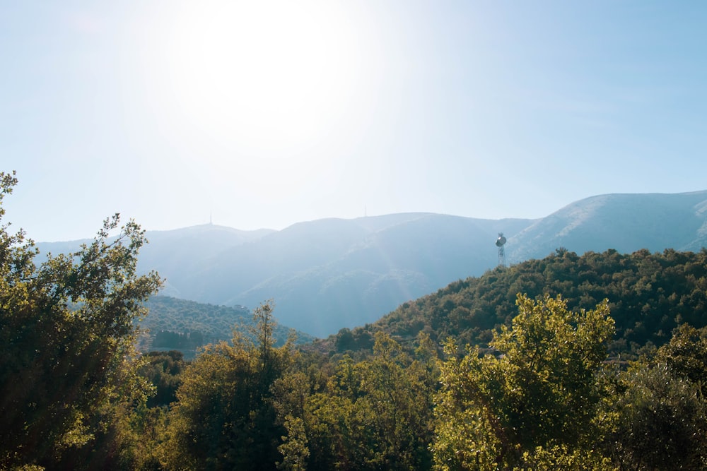 the sun is shining over the mountains and trees