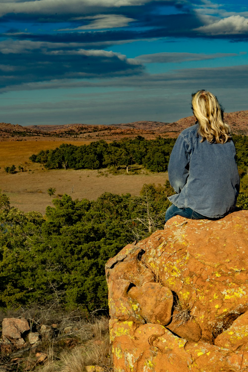 a woman sitting on top of a large rock
