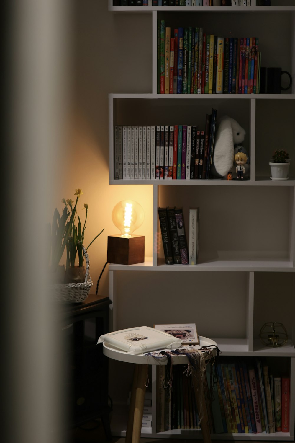 a bookshelf filled with lots of books next to a lamp