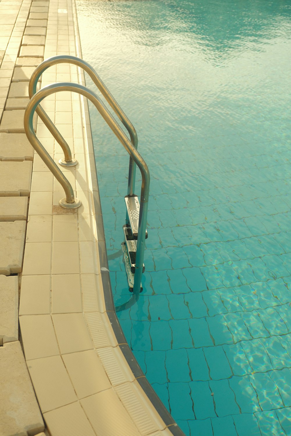 an empty swimming pool with a metal hand rail