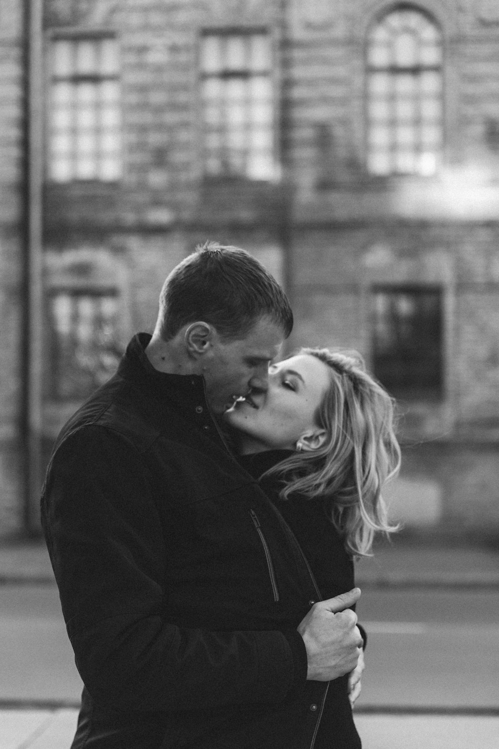 a man and a woman kissing in front of a building