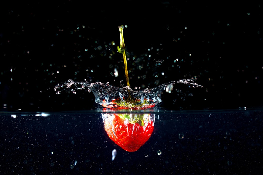 an apple falling into the water with a black background