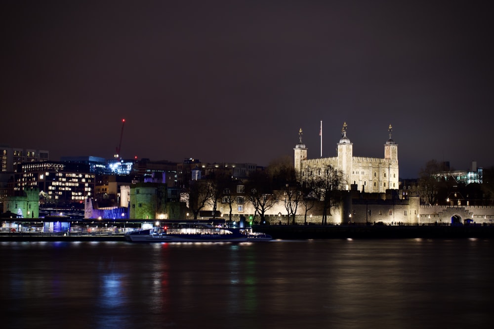 Una vista nocturna de una ciudad con un castillo al fondo