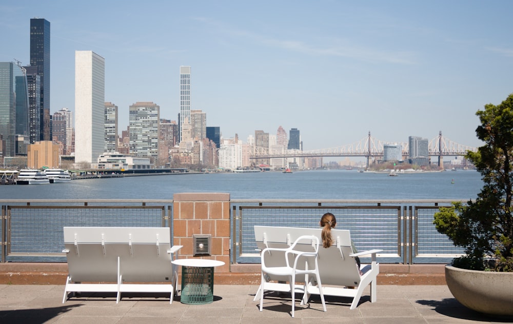 a woman sitting on a bench next to a body of water