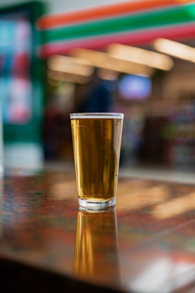 A chilled glass of golden beer with bubbles rising, set on a rustic wooden table.