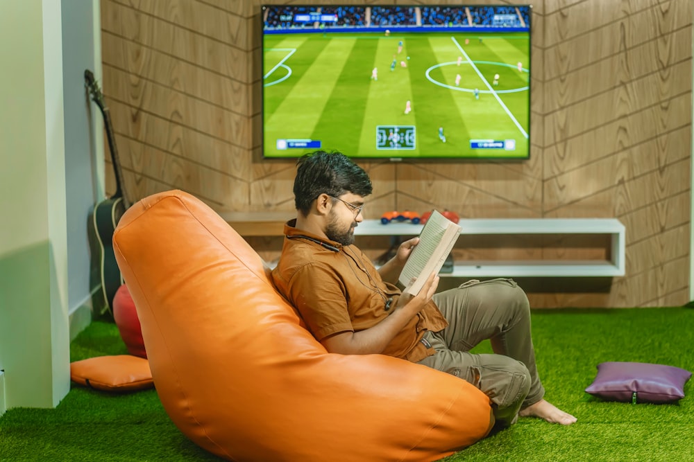 a man sitting on a bean bag chair reading a book